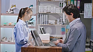 In a shoe shop happy smiling lady buying some shoes using the credit card to pay the seller good looking man giving the