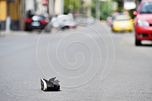 Shoe on the street with cars in background after accident