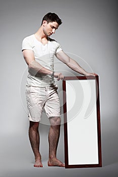 Shoeless Man Displaying White Board with Blank Spa