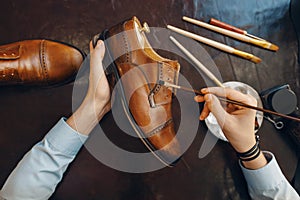 Shoemaker with brush tints shoes, footwear repair