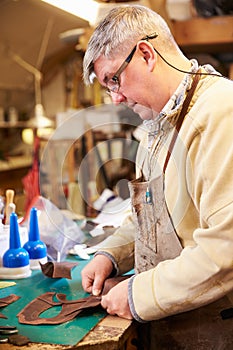 Shoemaker cutting and gluing leather in a workshop photo