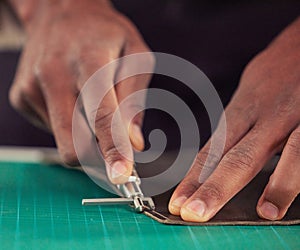 Shoemaker, hands and closeup to cut leather with tool in workshop for creative skill, small business or craft