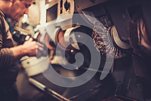 Shoemaker performs shoes in studio craft grinder machine.