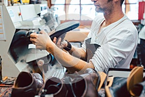 Shoemaker roughing the sole of a leather shoe