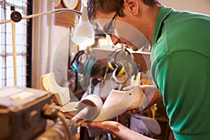 Shoemaker sanding shoe lasts in a workshop photo