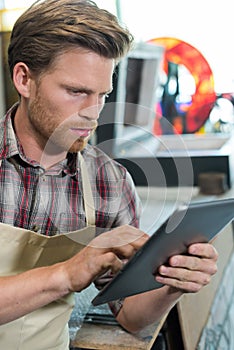 shoemaker using digital tablet in workshop