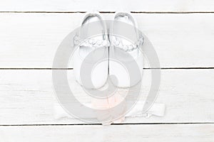 Shoes for babies and a bandage for hair on a white wooden background. Flat lay