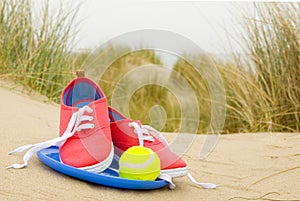 Shoes, ball and frisbee on beach landscape