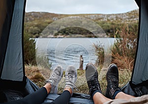 Shoes, camping and tent with a couple by a lake out in nature while hiking for adventure or travel together. Water