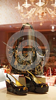 Shoes and handbag on display of luxury store, pink interior background