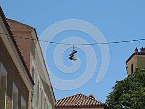 Shoes hanging on a wire under a blue sky.