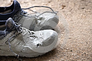 Shoes heavily stained in grey paint on an asphalt