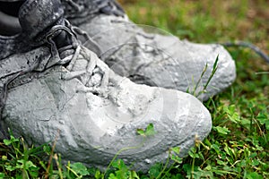 Shoes heavily stained in grey paint on the green grass