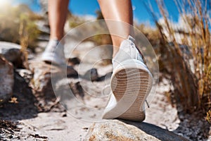 Shoes, hiking and fitness with a woman closeup walking up a mountain trail for exercise, cardio or adventure. Nature