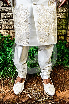 Shoes and legs of an Asian groom in a White traditional Indian groom