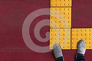 Shoes on yellow dot tactile paving for blind handicap on tiles pathway in japan, walkway for blindness people photo