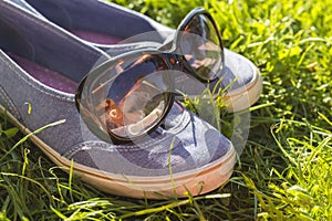 Shoes sneakers on the grass with sunglasses, summer relaxation and break concept