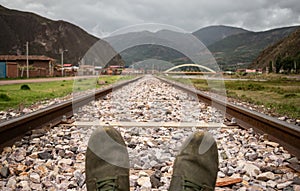 shoes on train tracks with nearby houses