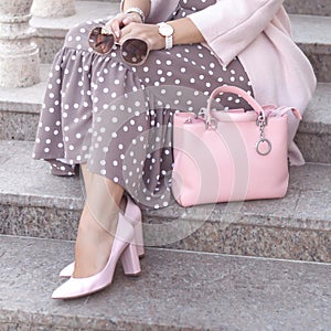 Shoes on women`s leg. pink shoes, bag. Sunglasses in the hands woman. Fashion ladies accessories, bracelets, eyeglasses.