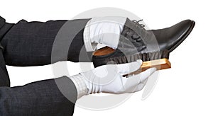 Shoeshiner in white gloves brushing black shoe