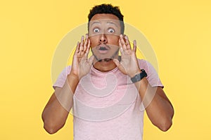 Shoked african american young man with hands in front of mouth scream over yellow background.