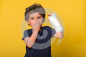 Shoked surprised and sad little boy in a cast. Child with a broken arm. Funny kindergarten kid after accident isolated