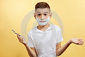 Shoking boy preparing for shaving face over yellow background