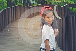 Shoot Asian cute little girl standing on wooden walway and feeling happiness.