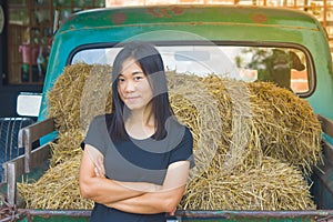 Shoot photo Asian woman portrait wear black t-shirt and cross one`s arm with straw on vintage car background.