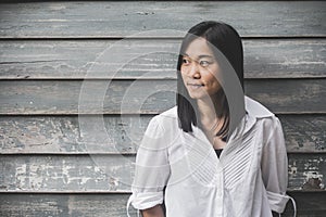 Shoot photo Asian woman portrait wear white shirt and looking sideways with wooden wall background.