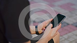 shooting advertising, a young guy in the park sits on a bench in black clothes and plays on the phone.