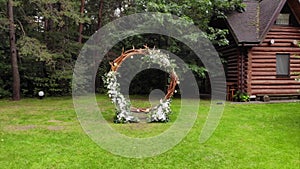 Shooting from aerial of an open area for a wedding ceremony with a flower arch and rows of benches on the lawn