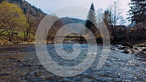 Shooting along the flowing water of a mountain river to the small bridge