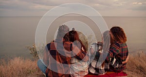 Shooting from behind: Two couples in love are resting on the seashore. Two couples in checkered shirts are hugging. Rest