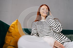 Shooting from below of laughing young woman with broken arm wrapped in gypsum bandage talking on smartphone with friends
