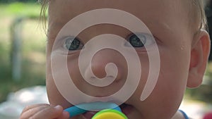 Shooting close-up beautiful girl with big blue eyes nibbles on a rattle