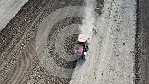 Shooting from drone flying over tractor on cultivated farm field