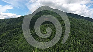 Shooting from a drone in the wild highlands. The approach to the mountain is covered with forest