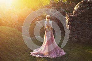 Shooting without a face, from the back. Wonderful princess with blond hair and a crown. is wearing an amazing light pink