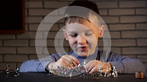 Shooting of little brunette boy playing with tin soldiers