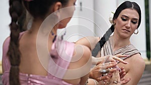 Shooting over shoulder of flexible woman dancing with partner Indian dance outdoors. Rack focus from one performer to