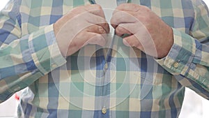 Shooting with a Person Dressing and Closing His Shirt Buttons. Man Closing His Shirt Buttons, One by One, Using His Hands.