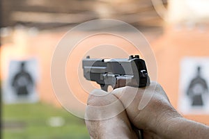 Shooting with a pistol. Man aiming pistol in shooting range.