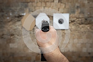 Shooting range, a pistol in a man's hand is pointed at a paper target