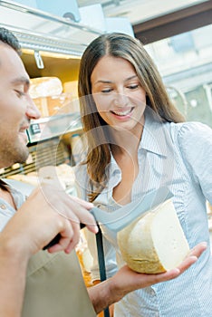 Shop assistant determining with customer where to slice cheese