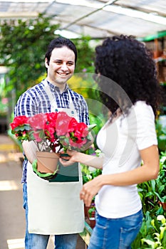 Shop assistant giving a flower pot to a customer