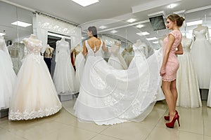 Shop assistant helps bride with wedding dress in boutique