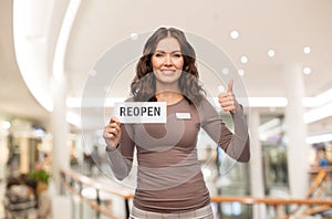 shop assistant with reopen sign showing thumbs up