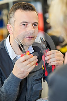 shop assistant showing two types pliers to customer