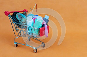 A shop basket with threads, sewing accessories and buttons. The background is made of light orange fabric.